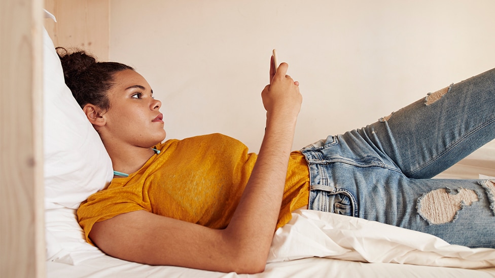 Wie willst du beraten werden? (Quelle: Klaus Vedfelt / DigitalVision / via Getty Images) Jugendliche liegt auf einem Bett und schaut auf ihr Smartphone