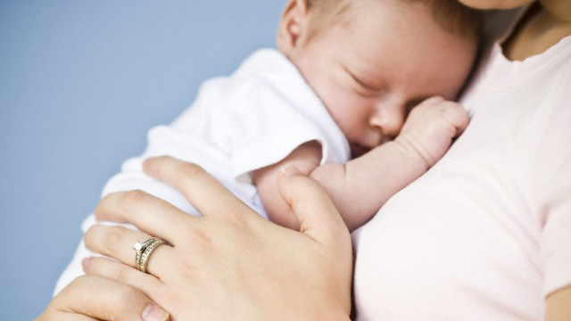 Mutter hält schlafenden Säugling im Arm