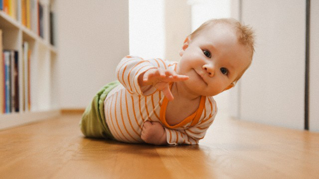 Wie sich das Baby entwickelt (Quelle: Radius Images/Corbis Images) Baby auf dem Boden robbend hebt eine Hand